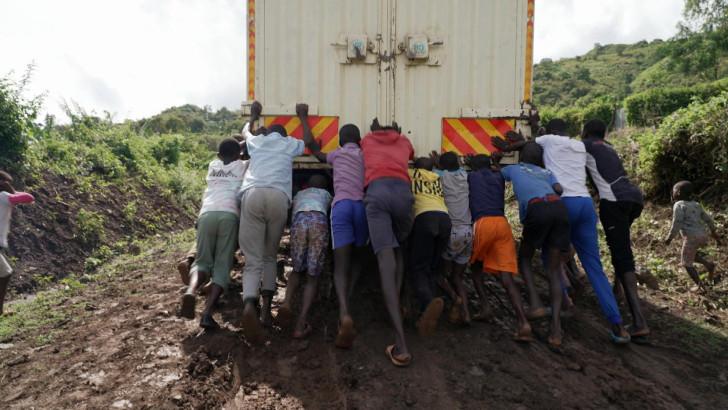 Des enfants poussant un camion sur une piste